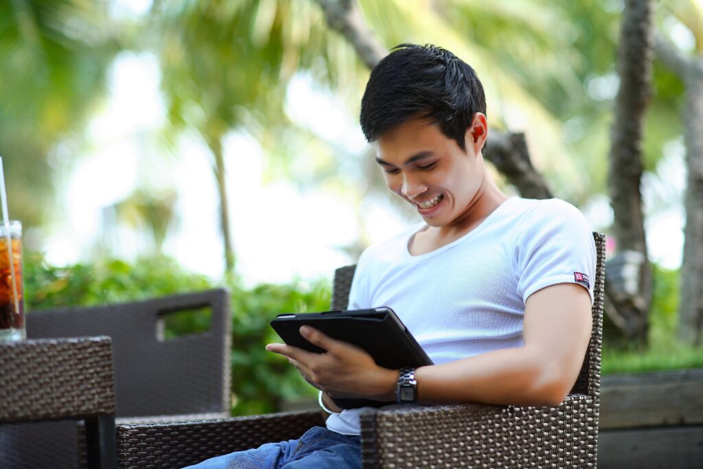 Man looking at iPad outside on chair